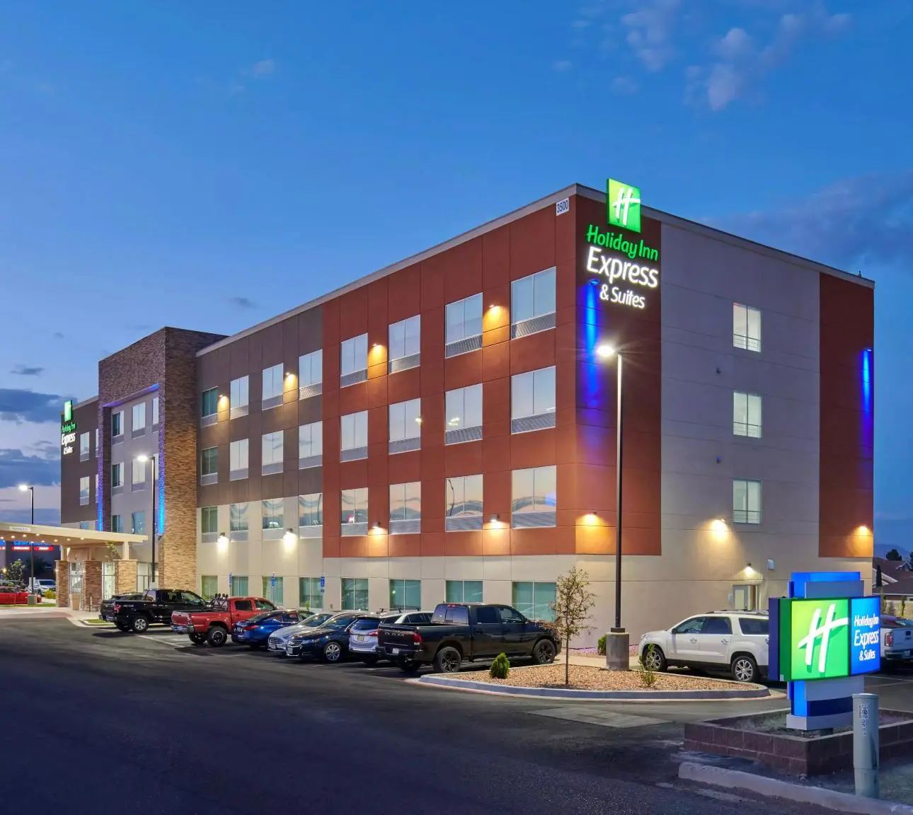 The Holiday Inn Express & Suites at dusk, its four storeys lit, with the parking court in front
